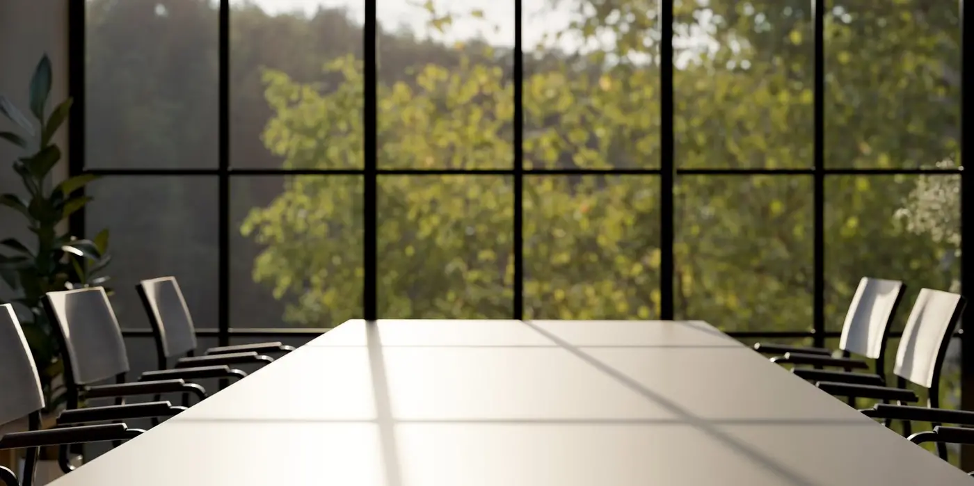A modern meeting room features a large meeting table and large window with a green mountain view.