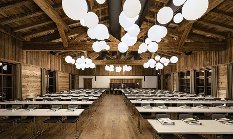 Großer rustikaler Seminarraum mit Holzbalken, langen Tischen und moderner Beleuchtung im alpinen Stil